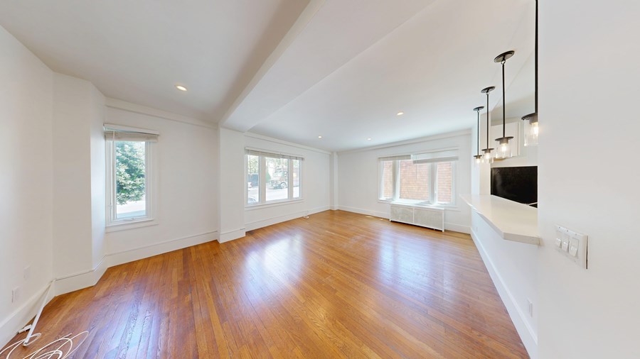 A spacious room with wooden floors and white walls.